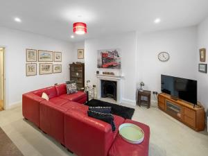 a living room with a red couch and a tv at Rooftops No83 in St. Leonards