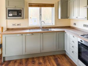 a kitchen with white cabinets and a sink at Lodge 3 - Uk51092 in Perranporth