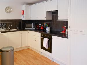 a kitchen with white cabinets and black counter tops at The Cottage in Rispond