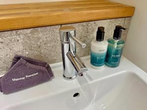 a bathroom sink with a faucet and two bottles of soap at The Cottage in Rispond
