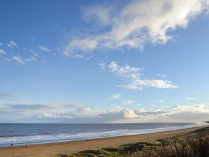 a beach with people walking on the sand and the ocean at Number 150 in Bessingby