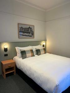 a bedroom with a large white bed with two pillows at Tourist Hotel Queanbeyan in Queanbeyan