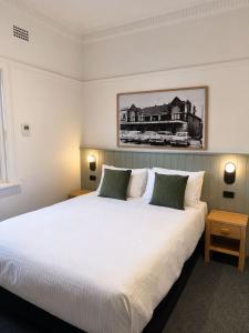 a bedroom with a large white bed with two lamps at Tourist Hotel Queanbeyan in Queanbeyan