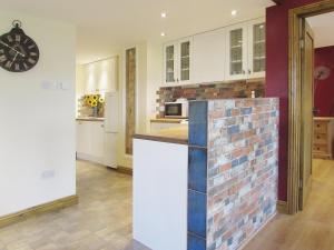 a kitchen with white cabinets and a brick wall at Sedge Lodge in Littleport