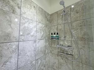 a shower with a shower head in a bathroom at The Byre in Rispond