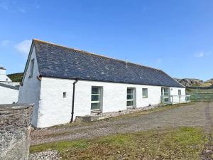 a white building with a black roof on a dirt road at The Byre in Rispond