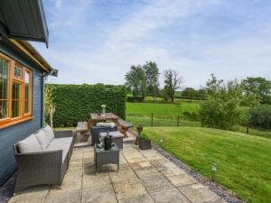 a patio with two wicker chairs and a firepit at Poundgate Lodge in Knighton
