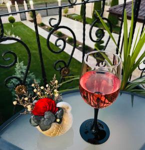 a glass of wine and a vase of flowers on a table at Vila Bya in 2 Mai +8 photos