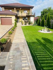 a house with a green yard with a walkway at Vila Bya in 2 Mai