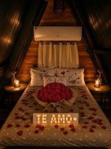 a bed with roses and a sign that says he amo at Cabanas Terra Nova in Três Coroas