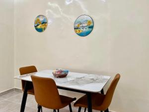 a table with four chairs and three plates on the wall at Midtown Appart Hôtel in Nouadhibou