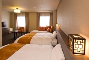 a hotel room with two beds and a television at Dormy Inn Nagasaki Shinchichukagai in Nagasaki