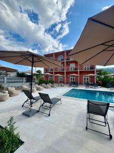 a pool with two chairs and two umbrellas at Guesthouse Orlović in Budva