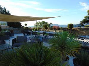 a patio with a table and chairs and a patio umbrella at Maison d'Hotes Les Palmiers in Gluiras
