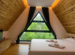 a bedroom with a large window and a bed with two towels at Riverside A-frame in Borşa