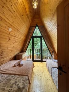 two beds in a room with a large window at Cozy Cottage JuFu in Mestia