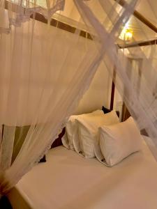 a bed with white pillows and a canopy at villa Senoa in Ahangama