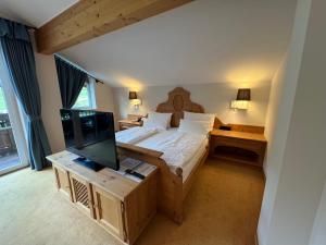a bedroom with a large bed and a television at Hotel Alpengasthof Löwen in Bad Hindelang
