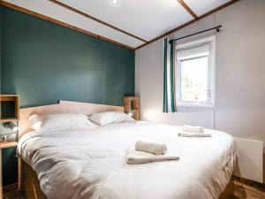 a bedroom with a large white bed with towels on it at Camping LANDAE in Ondres