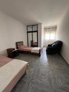 a room with two beds and a chair and a mirror at Spacious and sunny comfy apartment in Oran