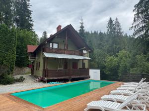 a house with a swimming pool in front of a house at Котеджі Сім Вітрів in Volosyanka