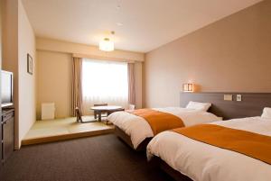 a hotel room with two beds and a window at Dormy Inn Nagasaki Shinchichukagai in Nagasaki +41 photos