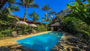 a swimming pool in a villa with palm trees at Pousada Portal do Cacau-Petfriendly in Camburi
