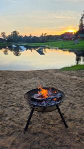 a fire pit on the beach next to a body of water at Antsu Puhkeala Matkamaja in Nüpli