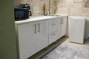 a white kitchen with a sink and a microwave at Da Vinci Apartmanok in Eger +26 photos