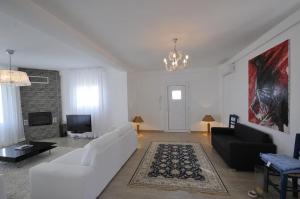 a living room with white furniture and a chandelier at Villa Lina Kerkira in Gouvia