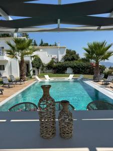 two vases sitting on a table next to a swimming pool at Villa Lina Kerkira in Gouvia