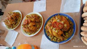 a table with three plates of food on it at Camp la mer de sable in Mhamid