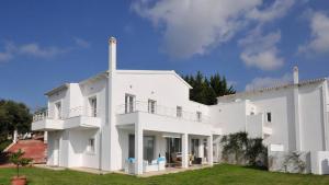 a large white house with a grass yard at Villa Lina Kerkira in Gouvia