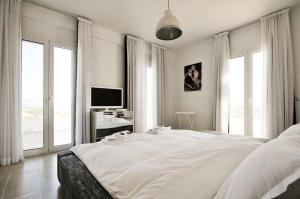 a white bedroom with a large white bed with windows at Villa Lina Kerkira in Gouvia +47 photos