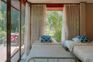 two beds in a room with a large window at SN Garden in Ban Bo Hin