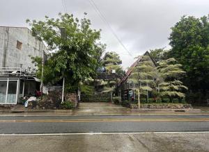 a building on the side of a street with a tree at Sikatel Hotel in Batac