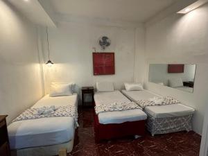 a room with three beds in a room at Sikatel Hotel in Batac