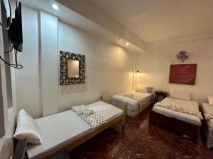 a room with two beds and a flat screen tv at Sikatel Hotel in Batac