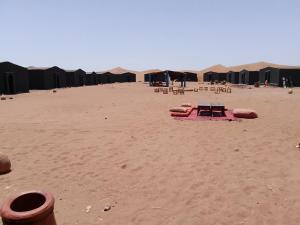 a beach with tables and chairs in the sand at Camp la mer de sable in Mhamid