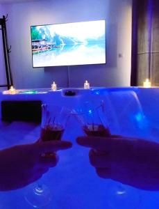 a person holding a wine glass in front of a tv at Love Room Emoi de toi in Sigean