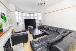 a living room with a leather couch and a television at Gateway to Gower in Dunvant