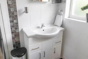 a white bathroom with a sink and a window at Gateway to Gower in Dunvant +17 photos