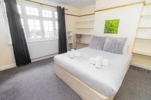 a bedroom with a large white bed and windows at Gateway to Gower in Dunvant
