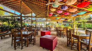 a restaurant with tables and chairs and umbrellas at Pousada Portal do Cacau-Petfriendly in Camburi