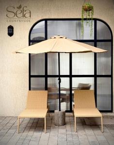 two chairs and an umbrella in front of a table at Sefa Countryside in Sukhi Sewānia