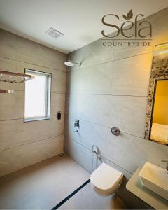 a bathroom with a toilet and a sink at Sefa Countryside in Sukhi Sewānia
