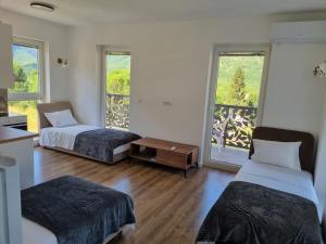two beds in a room with two windows at Nana Time Guesthouse in Vusanje