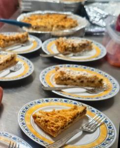 a table topped with plates of pie and forks at Agriturismo Maremma Amara in Saturnia