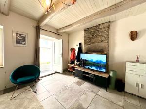 a living room with a television and a stone wall at Maison de pêcheur Quiberon in Quiberon