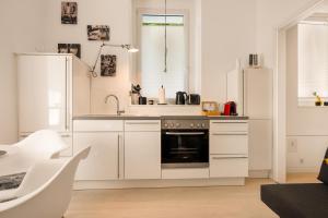 a white kitchen with a sink and a stove at Mola Apartments- Trendiges Apartment in der City-Nähe Dortmund-Terrasse-3 Gäste-WLAN in Herdecke +28 photos